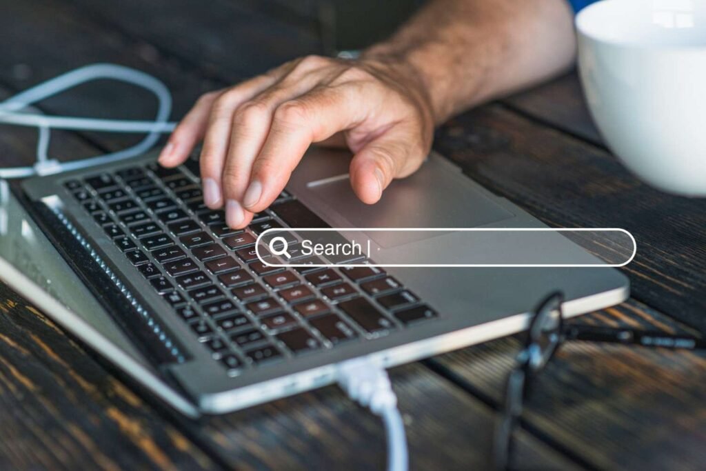 A professional working on a laptop with search icon on the interface.